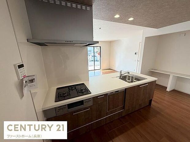 キッチンは開放的な空間で作業がしやすい設計です。三口コンロと広いシンクが特徴です。収納スペースも豊富で整理整頓しやすいです。明るい室内が魅力的です。室内全体が見渡せるキッチンレイアウトです。