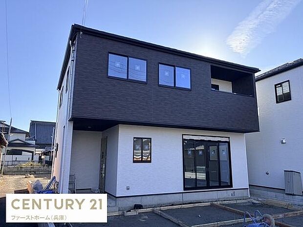 シンプルで洗練された外観が特徴の戸建住宅です。南向きの大きな窓から室内に明るい光が差し込みます。二階部分のダークトーンがアクセントとなっています。駐車スペースも確保されています。