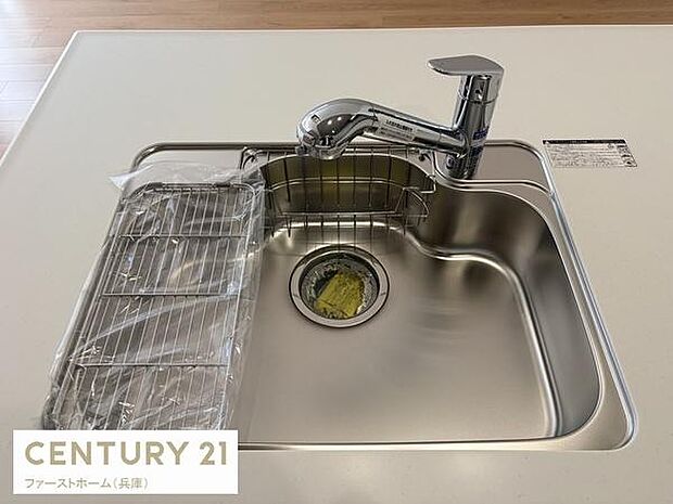 シンプルなデザインのキッチンシンクが清潔感を演出しています。水栓も使いやすそうな形状です。広々としたカウンター面が魅力的です。シンク横には便利な水切りラックも備えられています。