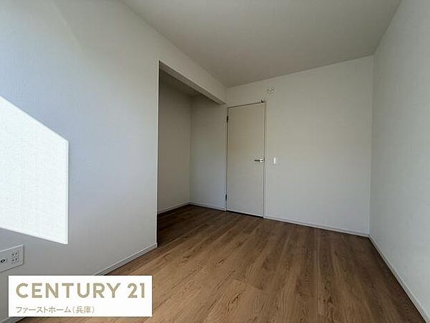 洋室はシンプルな白い壁と木目調の床が調和し清潔感があります。角に収納スペースが備わっているのもポイントです。明るい自然光が差し込み室内がすっきりとした印象です。