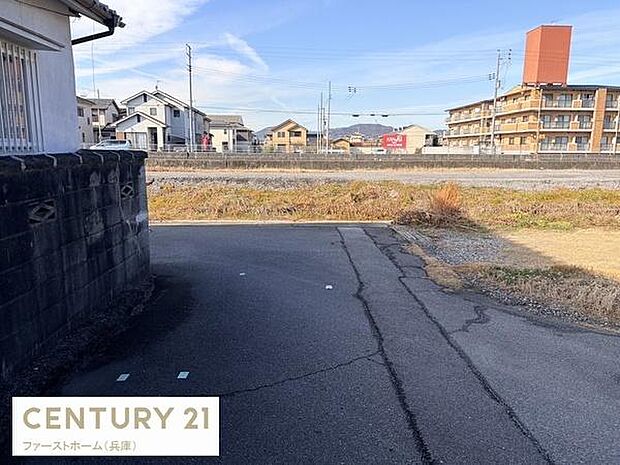 前面道路は広々しておりゆったりとした印象を受けます。周辺には住宅やマンションも建ち並び落ち着いた雰囲気です。日当たりの良い現地写真が確認できます。舗装された道路が安心感を与えます。