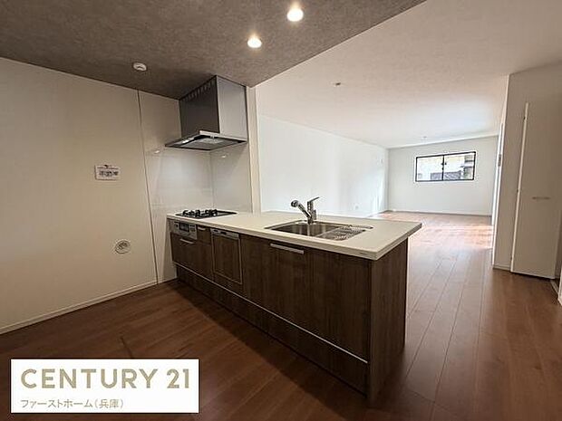 広々としたキッチンは木目調のデザインが特徴です。ダウンライトが空間を明るく演出します。対面型なのでリビングとのつながりを感じられます。使いやすいシンクとコンロが揃っています。