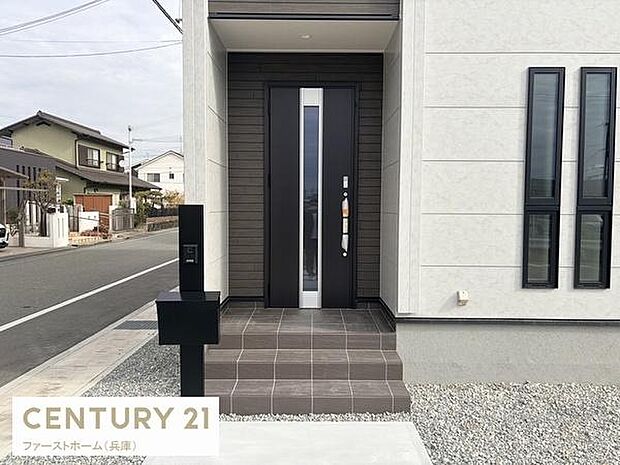 シンプルでモダンなデザインの玄関が目を引きます。幅広のドアが住まいに上質な雰囲気を加えています。タイル敷きの玄関アプローチが整然としています。建物の外観と調和した玄関スペースです。