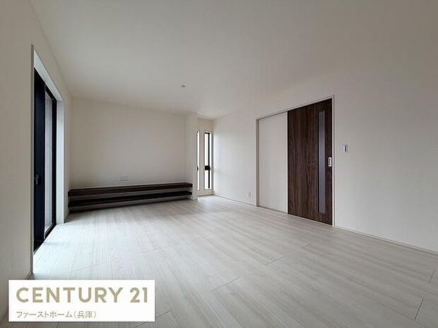 リビングは明るく開放的な空間が広がっています。床や建具の色合いが落ち着いた雰囲気を演出します。室内のデザインがシンプルで様々なインテリアに調和します。窓から差し込む自然光が心地よい印象を与えます。