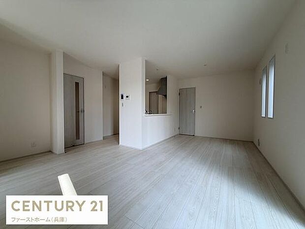 リビングには大きな窓があり明るい光が差し込む開放的な空間です。床の色合いが室内をさらに広く感じさせます。キッチンとのつながりも良好で日々の暮らしに便利です。