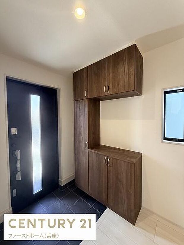 玄関には落ち着いた色合いのシューズボックスが備え付けられております。窓からは自然な光が差し込み明るい雰囲気です。玄関ドアは縦にスリットガラスが入っており採光とプライバシーを両立しています。