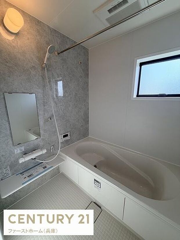 明るい照明と窓からの自然光で清潔感のあるバスルームです。壁面のグレー調デザインがアクセントになっています。浴槽はゆったりとしたサイズで日々の疲れをやわらげます。水まわりの手入れもしやすい仕様です。