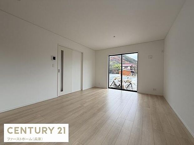 大きな窓から自然光がたっぷり入るリビングです。シンプルな内装が空間を広く見せてくれます。ナチュラルなフローリングが落ち着いた雰囲気を演出します。ダークなサッシがアクセントになっています。