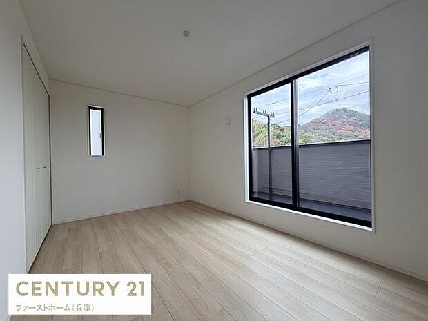 大きな窓から自然光がたっぷり差し込む寝室です。落ち着いた色合いのフローリングが空間を明るく見せています。バルコニーに面した開放感のある設計です。収納スペースも確保されています。