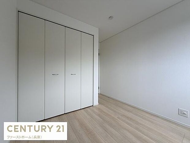 シンプルな内装が印象的な洋室です。白を基調としたクローゼットが空間に調和しています。ナチュラルなフローリングが落ち着いた雰囲気を演出しています。コンセントの配置も便利です。