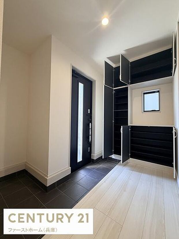 玄関は広々とした空間が広がり収納も豊富に設けられています。明るい照明と窓が印象的で清潔感を感じる内装です。シンプルなデザインが魅力的で快適に使えます。玄関ドア横のガラス部分がアクセントになっています。