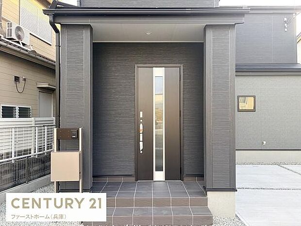 スタイリッシュな印象の玄関が特徴です。落ち着きのある色合いで住まいの雰囲気を引き立てます。段差が少なく出入りしやすい設計です。雨の日も安心な庇付きで快適です。周囲とのまとまりも感じられます。