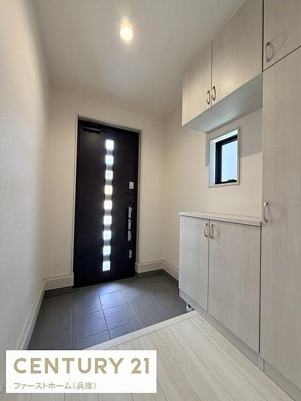 シンプルで清潔感のある玄関スペースです。玄関収納が豊富で使いやすさが感じられます。明るい照明と小窓からの自然光が空間をすっきりと演出します。靴の収納や整理がしやすい造りです。