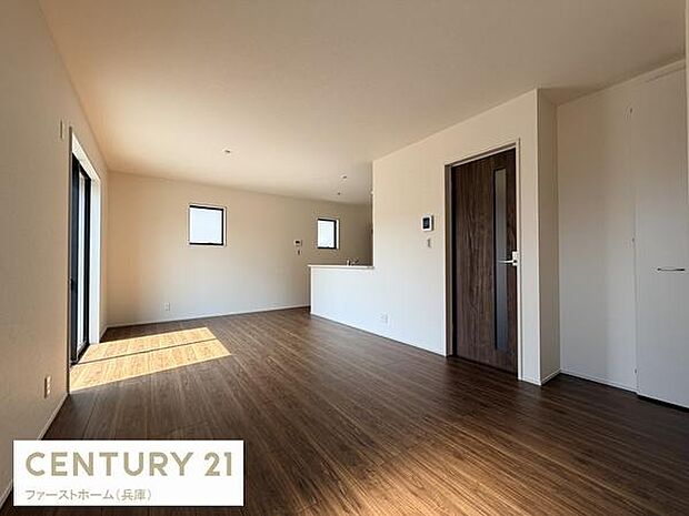 リビングはワイドな窓から自然光が差し込み部屋全体が明るい印象です。フローリングは落ち着いた色合いで空間に統一感があります。キッチンとのつながりもスムーズなレイアウトです。