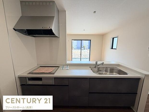 シンプルで使いやすいキッチンです。窓があり明るい雰囲気が広がります。作業スペースも広く収納も充実しています。IHコンロと換気扇が設置されています。清潔感のある空間です。