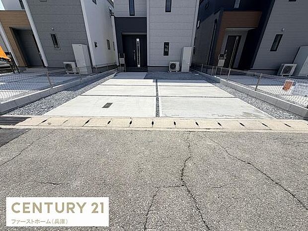 コンクリート仕上げの駐車場は車の出し入れがしやすい設計です。両側にはしっかりとしたフェンスが設置されています。幅も十分に確保されており複数台の駐車にも対応しています。