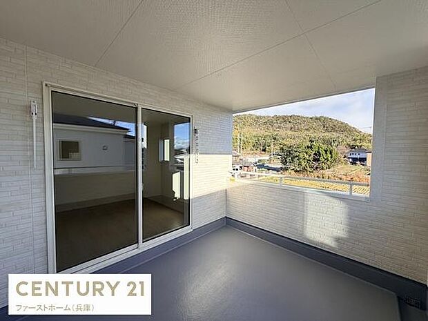 開放感のある広々としたバルコニーです。屋根付きで天候を気にせず利用できます。周囲の景色も望めるスペースとなっています。大きな窓から室内への採光も確保されています。シンプルで使いやすいデザインです。