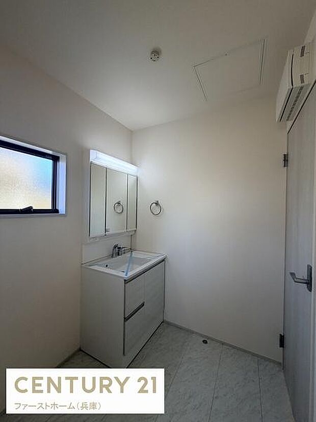 シンプルで清潔感のある洗面台が設置されています。壁付けの鏡が空間を広く感じさせます。小窓から自然光が入り室内が明るい印象です。収納スペースも確保されており使い勝手に配慮されています。