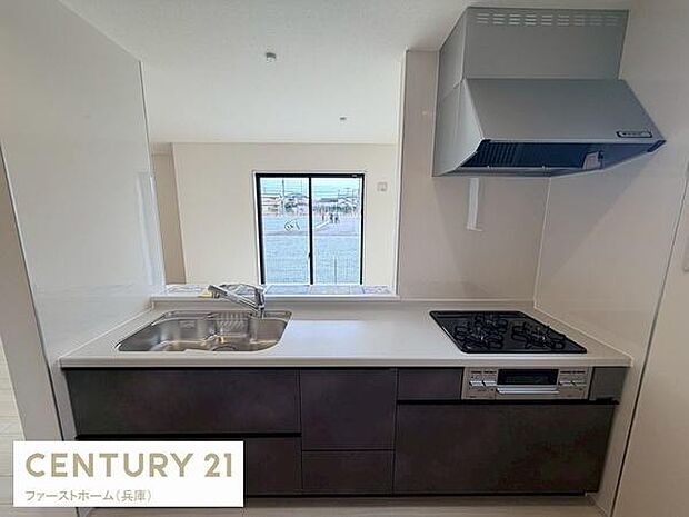 シンプルなデザインが特徴のキッチンです。3口コンロ付きで調理がしやすい仕様です。窓から外を見渡せる開放感があります。収納スペースも確保されています。機能的なレイアウトが印象的です。