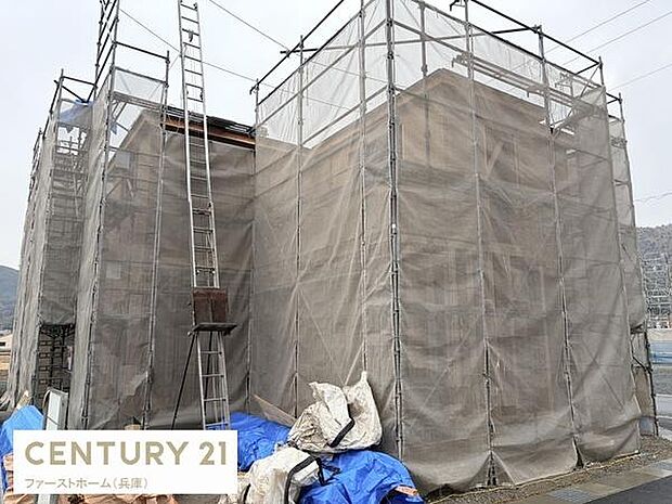 建設中の住まいがしっかりと足場やシートで保護されていて作業の進捗状況が確認できる現場の様子です。広い敷地で作業スペースも確保されています。資材置き場も整然としている印象です。