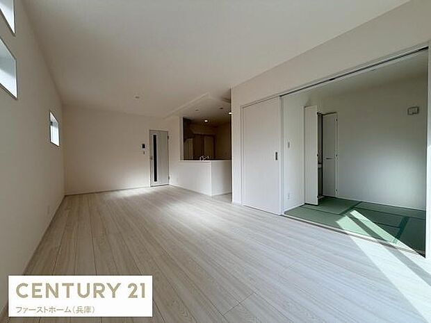 リビングは明るい色調のフローリングが広がり開放感のある空間です。隣接する和室と一体的に使える設計が特徴です。小窓が配置されており自然光が取り入れやすくなっています。