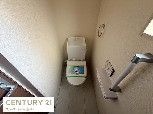 採光のある明るい空間でトイレには手すりが設置されており安心してご利用いただけます。ペーパーホルダーやリモコンも壁に配置され使いやすさが配慮されています。清潔感のあるクロスと床材が印象的です。