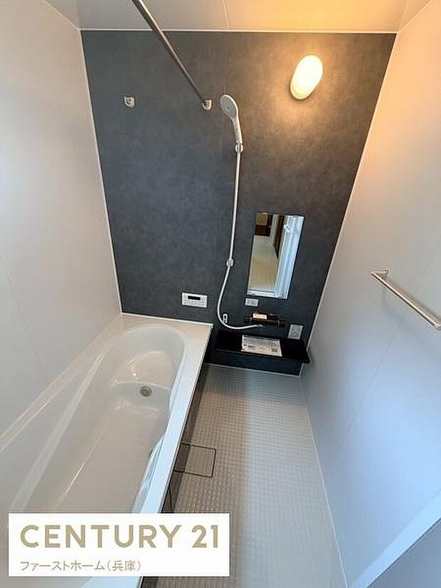 シンプルで清潔感のあるバスルームです。壁面のアクセントカラーが空間を引き締めています。浴室内のスペースも十分確保されています。手元に操作パネルが配置されていて便利です。