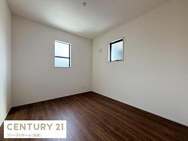 洋室は白を基調としたシンプルな内装で落ち着いた雰囲気が感じられます。窓が2面あり室内には自然光が差し込みます。床は濃い色味のフローリングで高級感が漂っています。