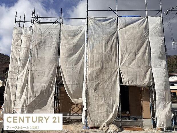 現在建築中の物件で外観の様子をご確認いただけます。足場とシートでしっかり覆われており作業の進捗が感じられる一枚です。新築のため今後の仕上がりが楽しみな物件です。