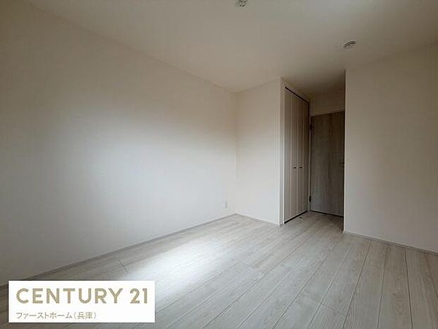 明るい光が差し込む寝室です。クローゼットが備わっており収納スペースも確保されています。シンプルな内装でお手入れもしやすい空間です。落ち着いた色合いの床が印象的な一室です。