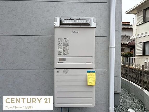 建物外壁に設置された給湯器の様子です。スッキリとしたデザインが特徴で操作も見やすくまとめられています。周囲は整備された敷地で建物の手入れが行き届いています。設備の状態も写真から確認できます。
