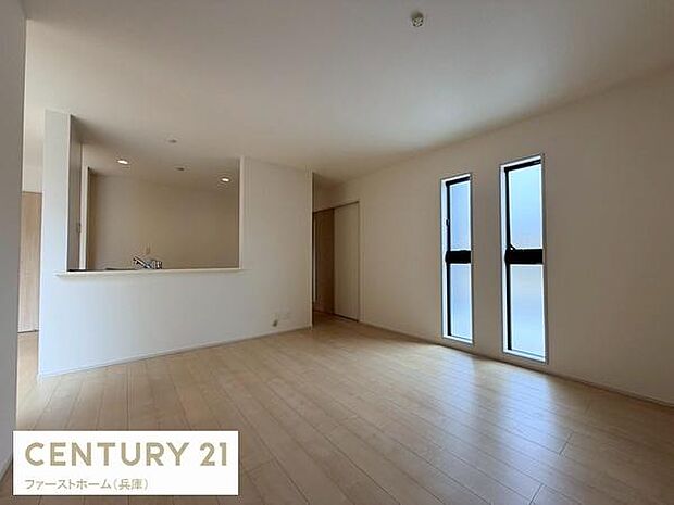 リビングには大きな窓が配置されており室内全体が明るく感じられます。床はナチュラルな色合いでさまざまなインテリアと調和します。オープンなキッチンとの繋がりがあり空間が広く活用できます。