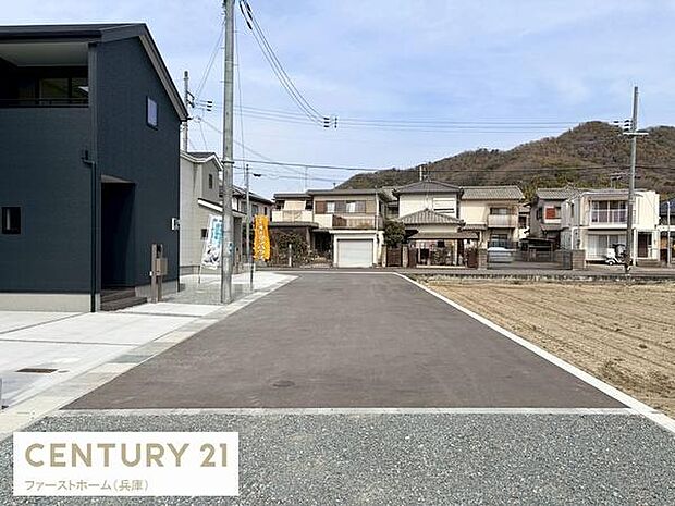 前面道路は幅がしっかり確保されており車の出入りもスムーズに行えます。周囲には住宅が並び落ち着いた雰囲気です。電柱や配線も整然としており道沿いも明るく見通しが良い印象です。