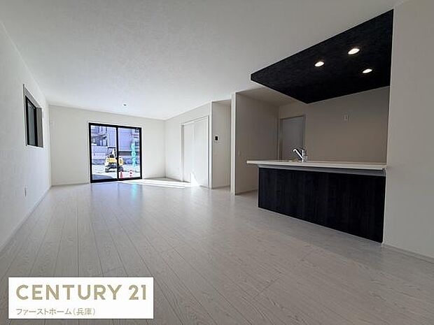 開放感のあるリビングスペースです。大きな窓からは自然光がたっぷりと差し込みます。ホワイトを基調とした内装が印象的です。ダークカラーのキッチンがアクセントとなっています。