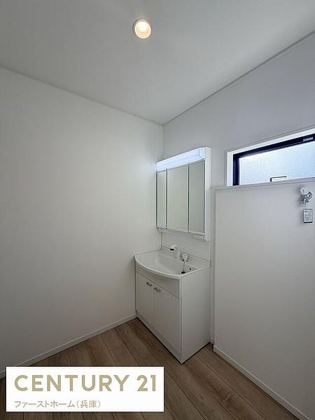 シンプルなデザインの洗面台が空間をすっきりと見せています。ナチュラルな床材が清潔感を演出。大きめの鏡が使い勝手にも配慮されています。窓から採光も入り明るい印象です。収納力もしっかり確保されています。