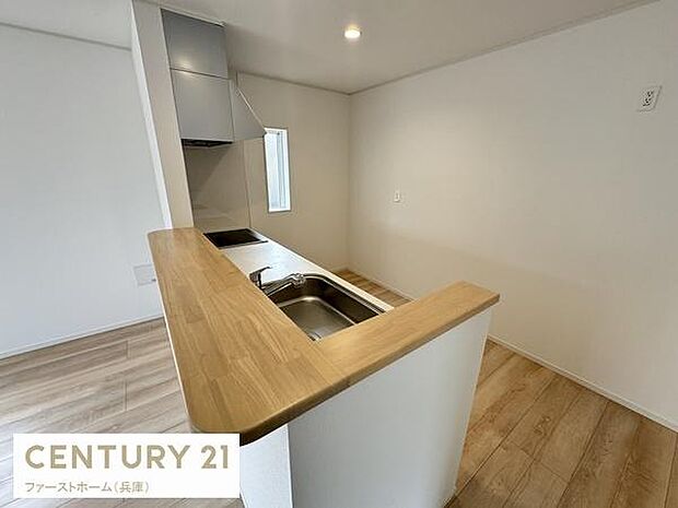 ナチュラルな色合いのカウンターが明るい印象を与えます。作業スペースが広く使いやすい形状です。小窓付きで換気もスムーズに行えます。シンプルで清潔感のあるキッチンです。収納スペースも確保されています。