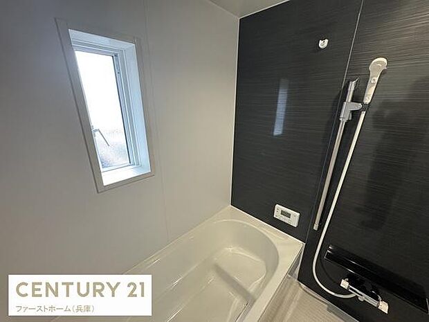 浴室には窓が設置されており換気がしやすい空間です。シンプルなデザインが特徴のバスルームとなっています。ブラックのアクセントパネルがスタイリッシュな印象を与えます。給湯リモコンも備わっています。