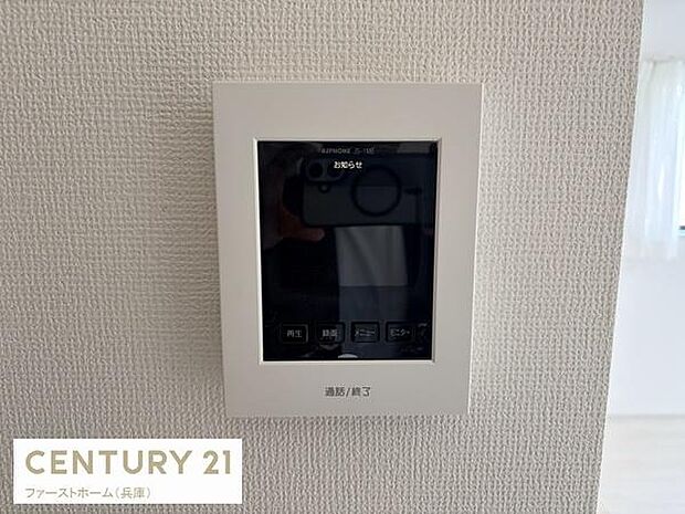 壁に設置されたインターホンモニターが見受けられます。モニター付きで来訪者の確認がしやすい仕様となっております。シンプルなデザインで壁紙と調和しています。操作ボタンも視認しやすい配置です。