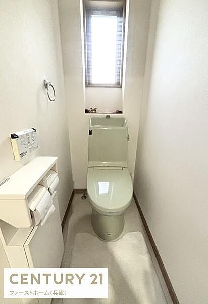窓から自然光が差し込む明るいトイレです。清潔感があり手洗いスペースも備え付けられています。壁面にリモコンが設置され使い勝手も考慮されています。コンパクトながらもスッキリとした空間です。