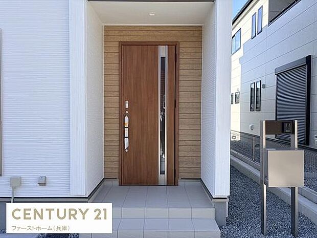 洗練されたデザインの玄関が印象的です。広々としたタイルスペースで開放感を感じられます。木目調のドアが外観にアクセントを与えておりモダンな雰囲気を演出しています。