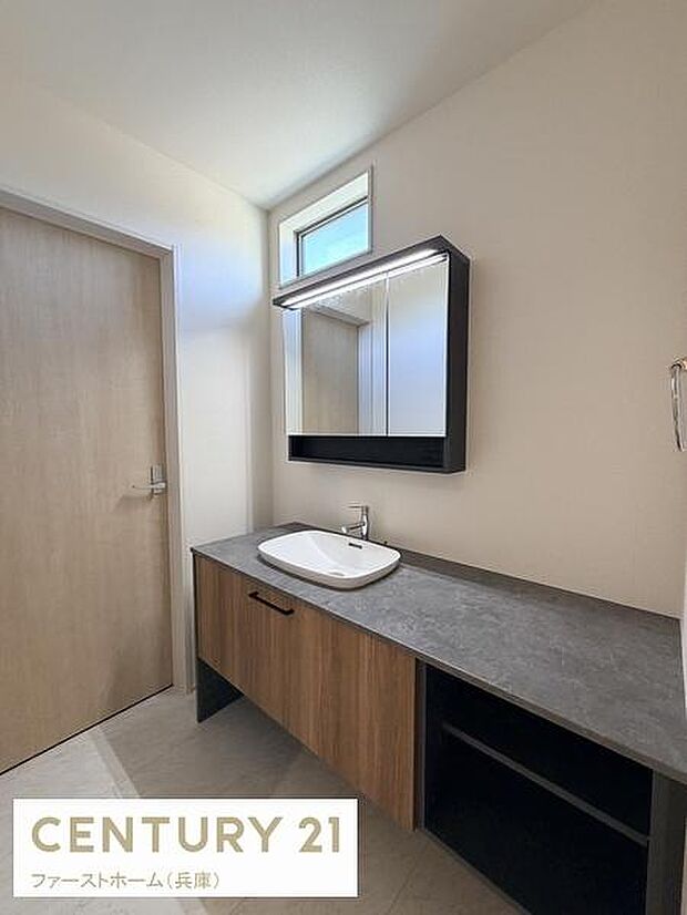 広々とした洗面スペースで収納も充実しています。窓があり自然光が差し込みます。シンプルなデザインが特徴です。洗面台の配置がスムーズな動線を確保しています。使いやすさを追求した洗面所です。