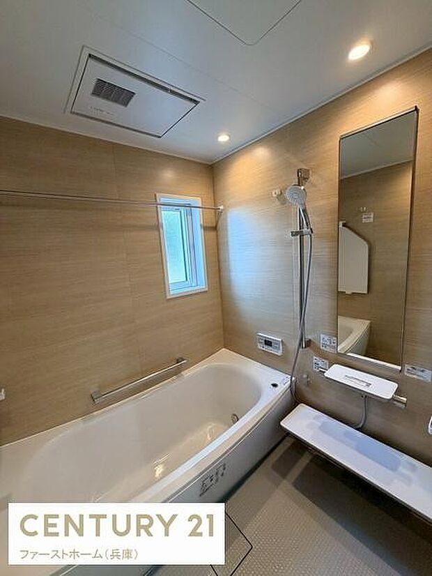 明るい木目調の壁が特徴的なバスルームです。浴槽はゆったりとしたサイズ感です。小窓があるため適度な採光と換気が可能です。収納スペースも確保されています。シンプルで使いやすい設計です。