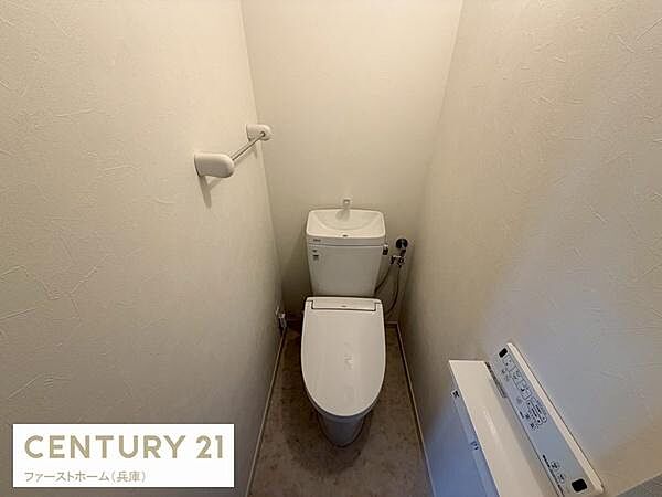 シンプルですっきりとした内装のトイレです。備え付けのペーパーホルダーが設置されています。壁や床も清潔感があります。換気のしやすいレイアウトです。操作パネルが使いやすい位置にあります。