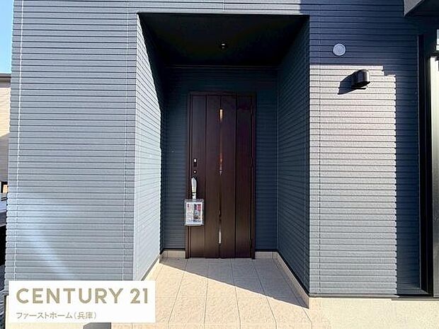 落ち着いた色合いの外観が印象的な玄関です。玄関ポーチは天井に覆われており雨の日も快適に出入りできます。玄関扉のデザインがシンプルでモダンな雰囲気が漂います。照明付きで夜間の出入りも安心です。