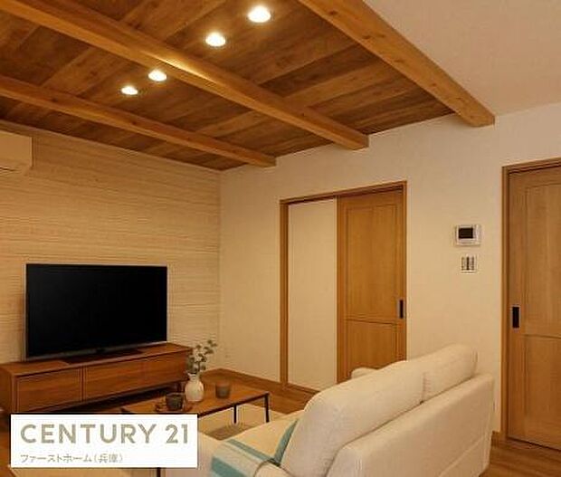 木目調の天井が特徴的な落ち着いた雰囲気のリビングです。温かみのある木製ドアや建具が空間に統一感を与えています。シンプルで整った内装が印象的です。照明も複数設置されており快適に過ごせます。