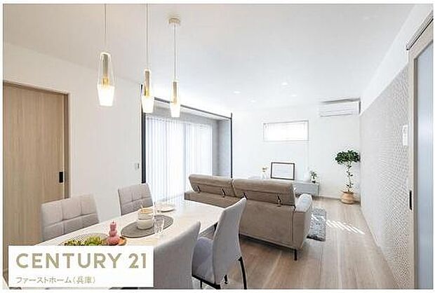 リビングには明るい光が差し込み全体的に清潔感のある雰囲気です。シンプルなインテリアが空間を広く感じさせます。床や壁の色合いが統一されており落ち着いた印象です。エアコンや照明も設置されています。