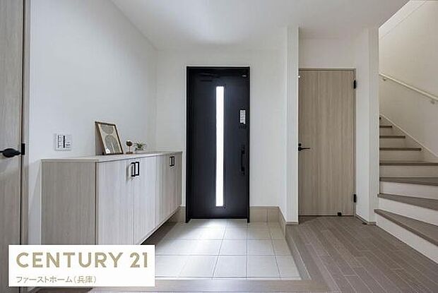 玄関にはシンプルなデザインのドアが採用されスタイリッシュな印象を与えます。ゆとりある空間で収納も確保されています。明るい色合いの床とシューズボックスが調和しています。動線もしっかり考えられた配置です。