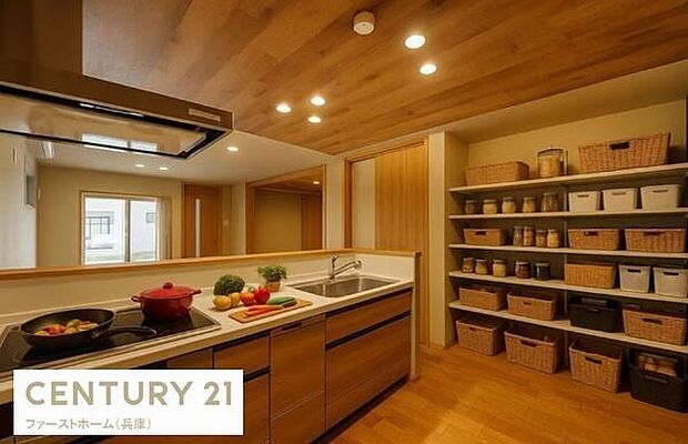 木目調の天井と床が調和した落ち着いたキッチンです。広々とした作業スペースとたっぷり収納棚が特徴です。明るい照明が空間全体を引き立てています。アイランド型カウンターも便利です。