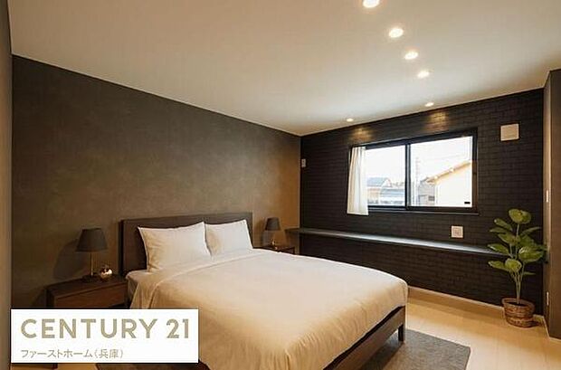 落ち着いたトーンの壁と照明が印象的な寝室です。大きな窓から自然光が入り室内が明るい印象です。観葉植物がさりげなく配置されすっきりとした空間になっています。ベッドサイドの照明もアクセントになっています。