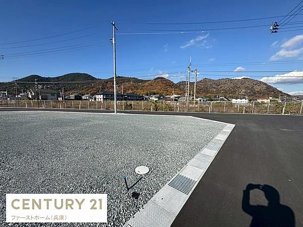 広々とした現地土地写真です。周囲に建物が少なく開放感を感じられます。道路に面しており車の出入りもしやすい区画です。電柱やインフラ設備も整っています。